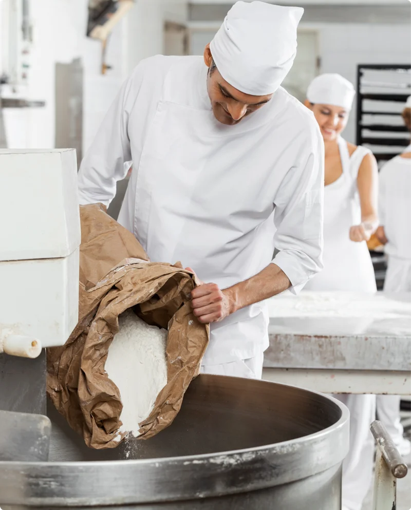 impiegato di laboratorio che versa mix di farina in planetaria